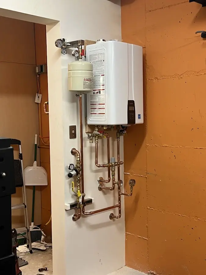 Plumbing technician inspecting water heater connections in Rothschild